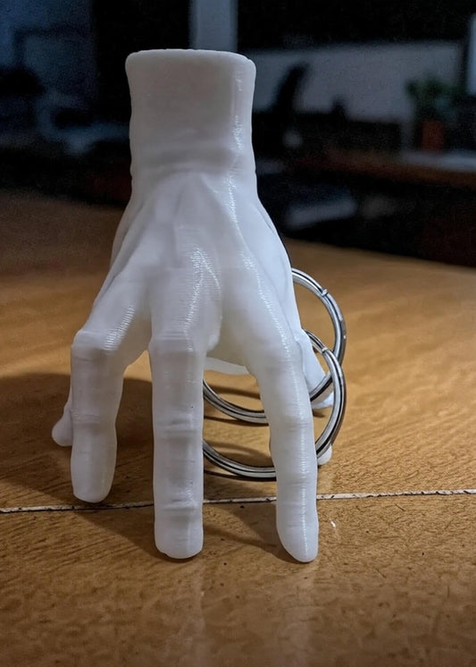 3D-printed hand-shaped keychain on a wooden surface